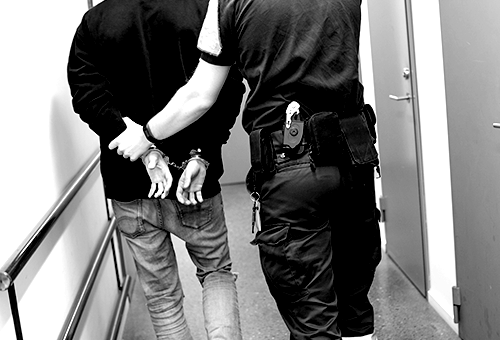 person in handcuffs being led by a police officer